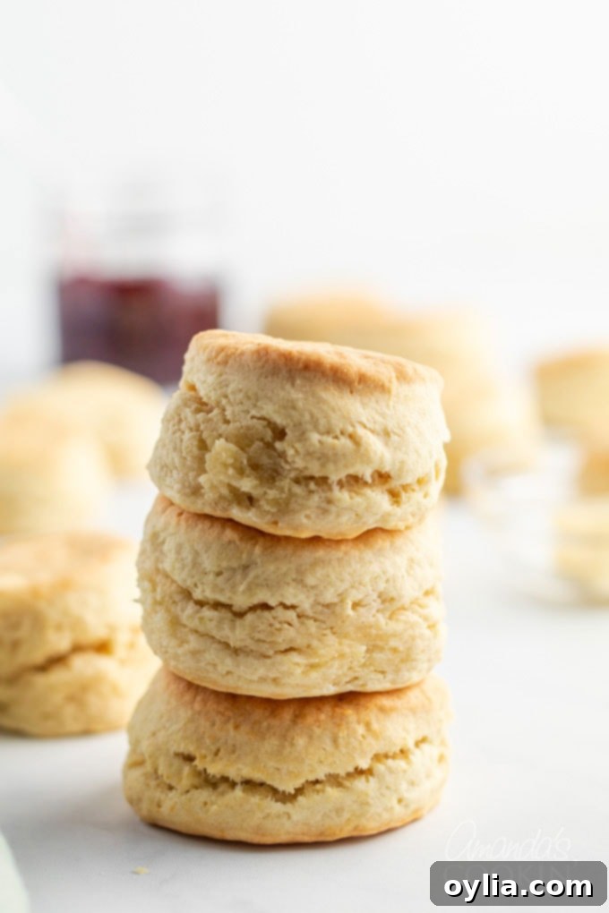 A tall stack of golden, freshly baked homemade biscuits, showcasing their fluffy texture and perfect rise