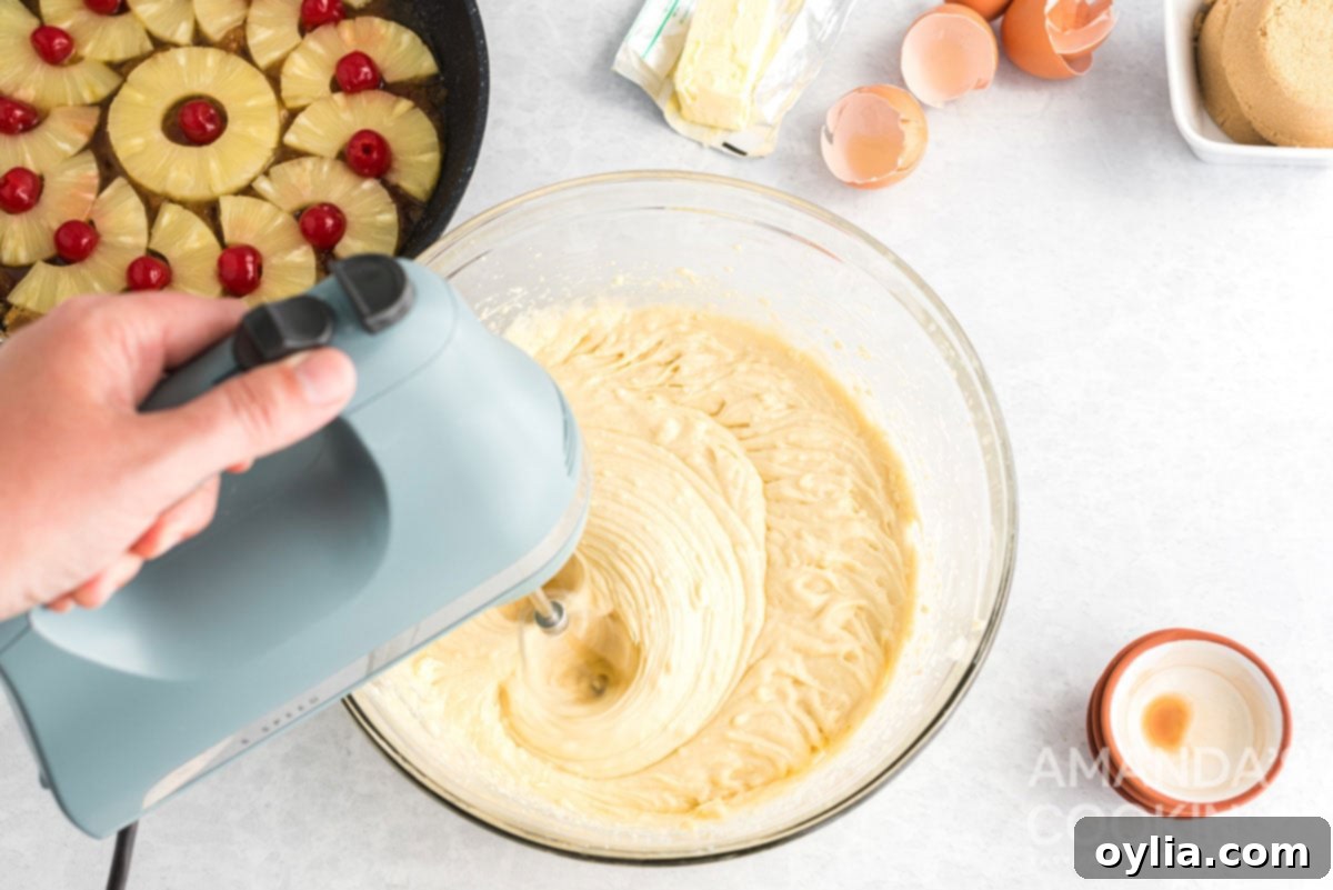 Cake batter being mixed with electric beaters in a bowl, achieving a smooth consistency.
