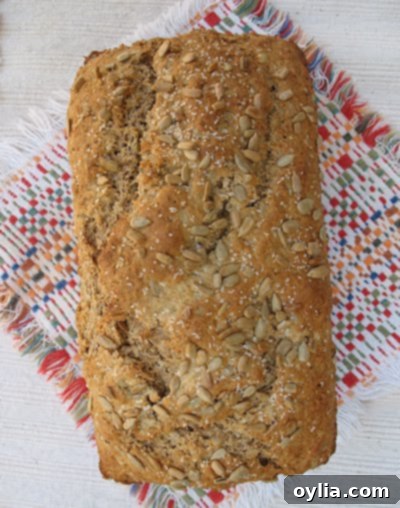 A beautifully baked full loaf of sunflower whole wheat quick bread, resting on a wooden surface.