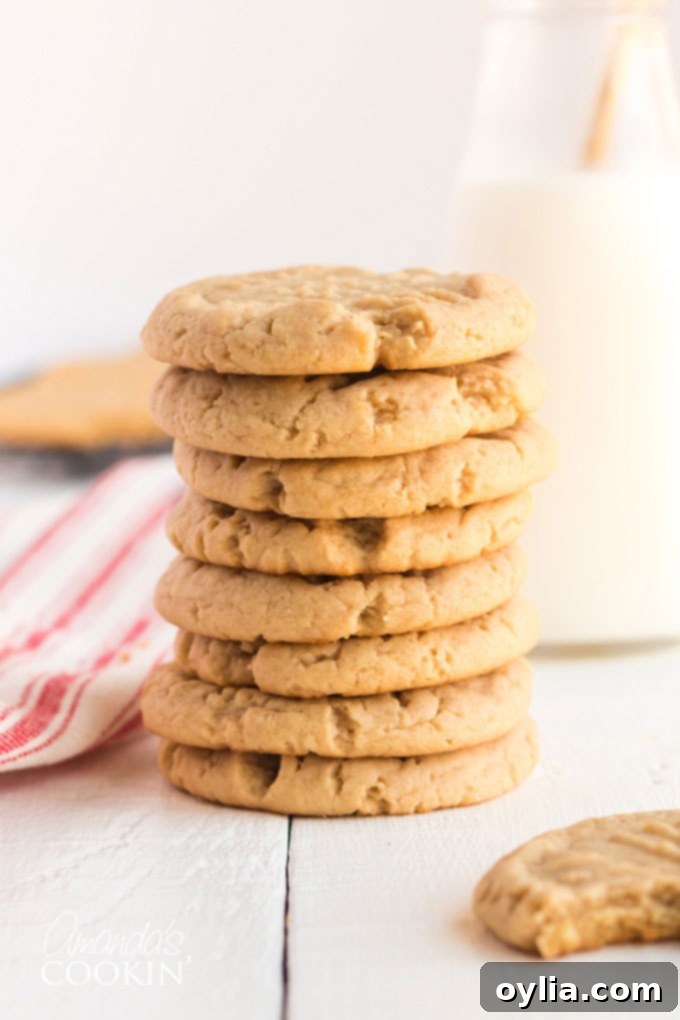 Stack of freshly baked soft peanut butter cookies next to a bottle of milk, highlighting a perfect snack.