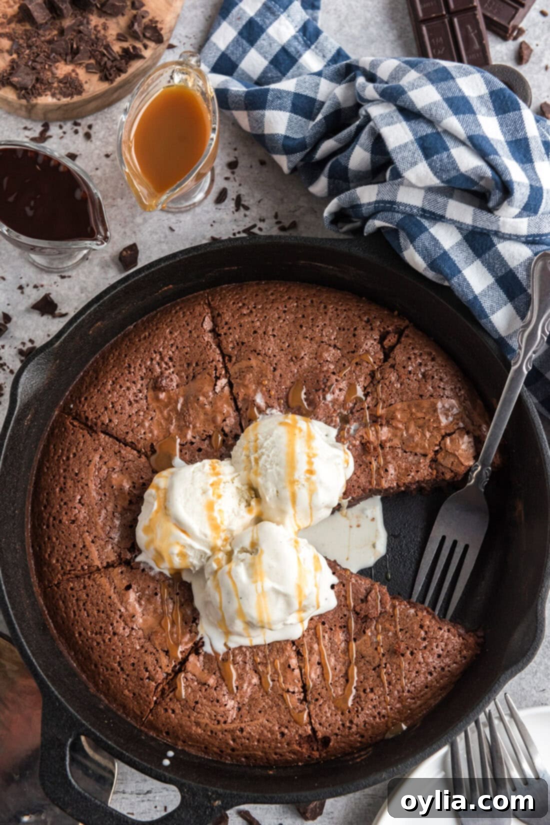 Rich, fudgy brownies baking in a cast iron skillet, with a slice removed to show the gooey center and a fork resting in the pan, ready to be devoured.