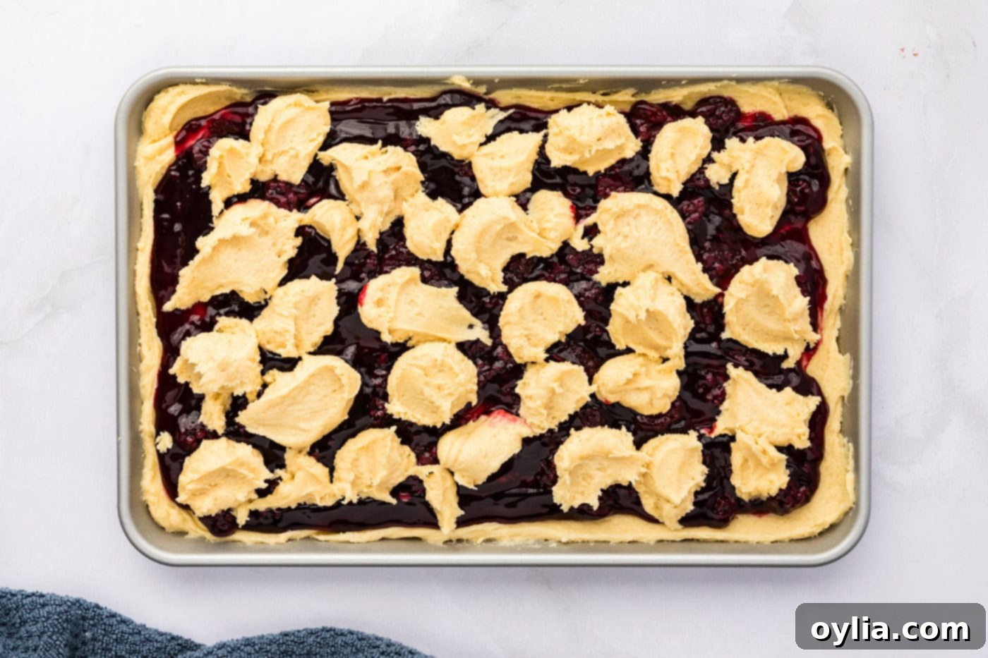 Dollops of cookie dough batter placed on top of the blackberry pie filling layer