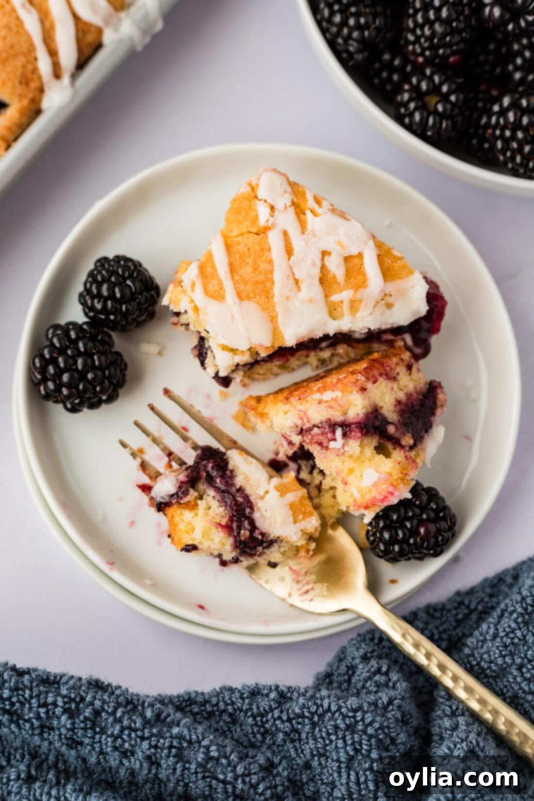 A single Blackberry Pie Square broken in half on a plate with a fork, showing the moist interior