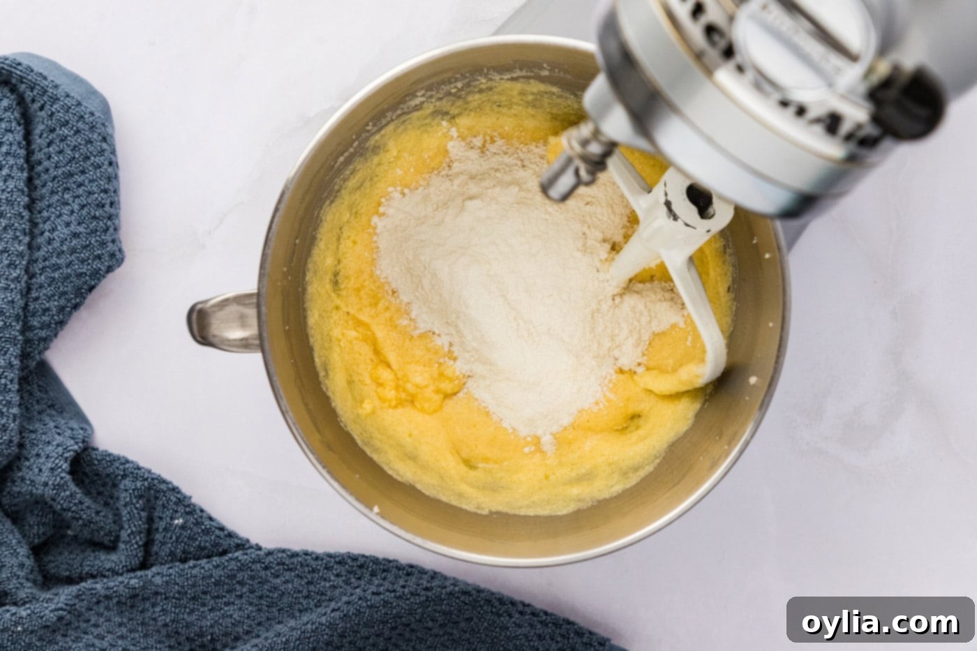 Flour mixture being slowly added to the butter and sugar mixture in a stand mixer bowl