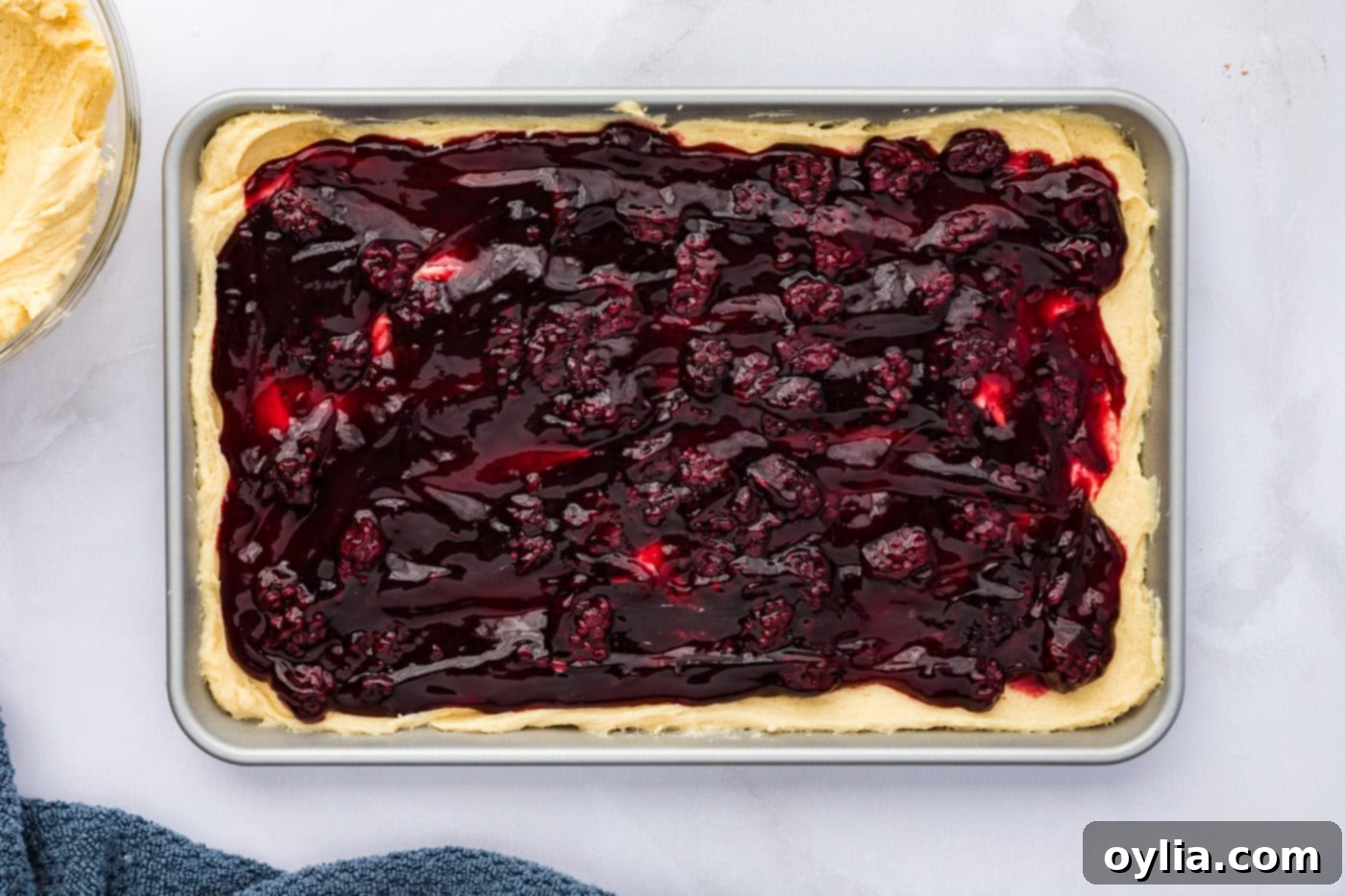 Blackberry pie filling spread over the cookie dough base in a baking pan