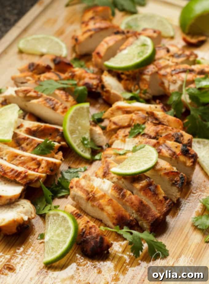 Perfectly sliced Chile Lime Chicken on a cutting board, garnished with fresh lime.