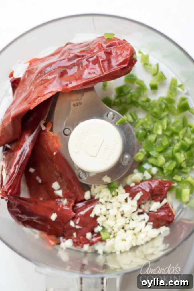 Step-by-step: Add rehydrated chiles, jalapeno, and garlic to a food processor.