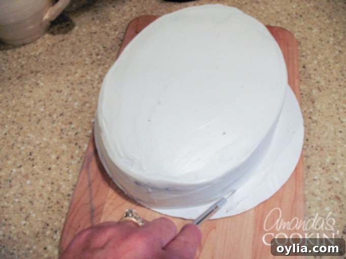 A close up photo of a cake resting on cardboard that is being cut with an x-acto knife.