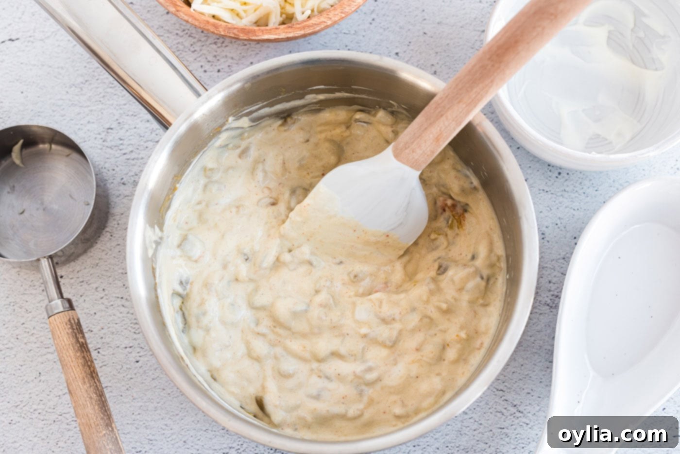 A close-up of the rich, creamy green chile sour cream sauce, featuring melted Monterey Jack cheese, perfectly blended and ready for enchilada assembly.