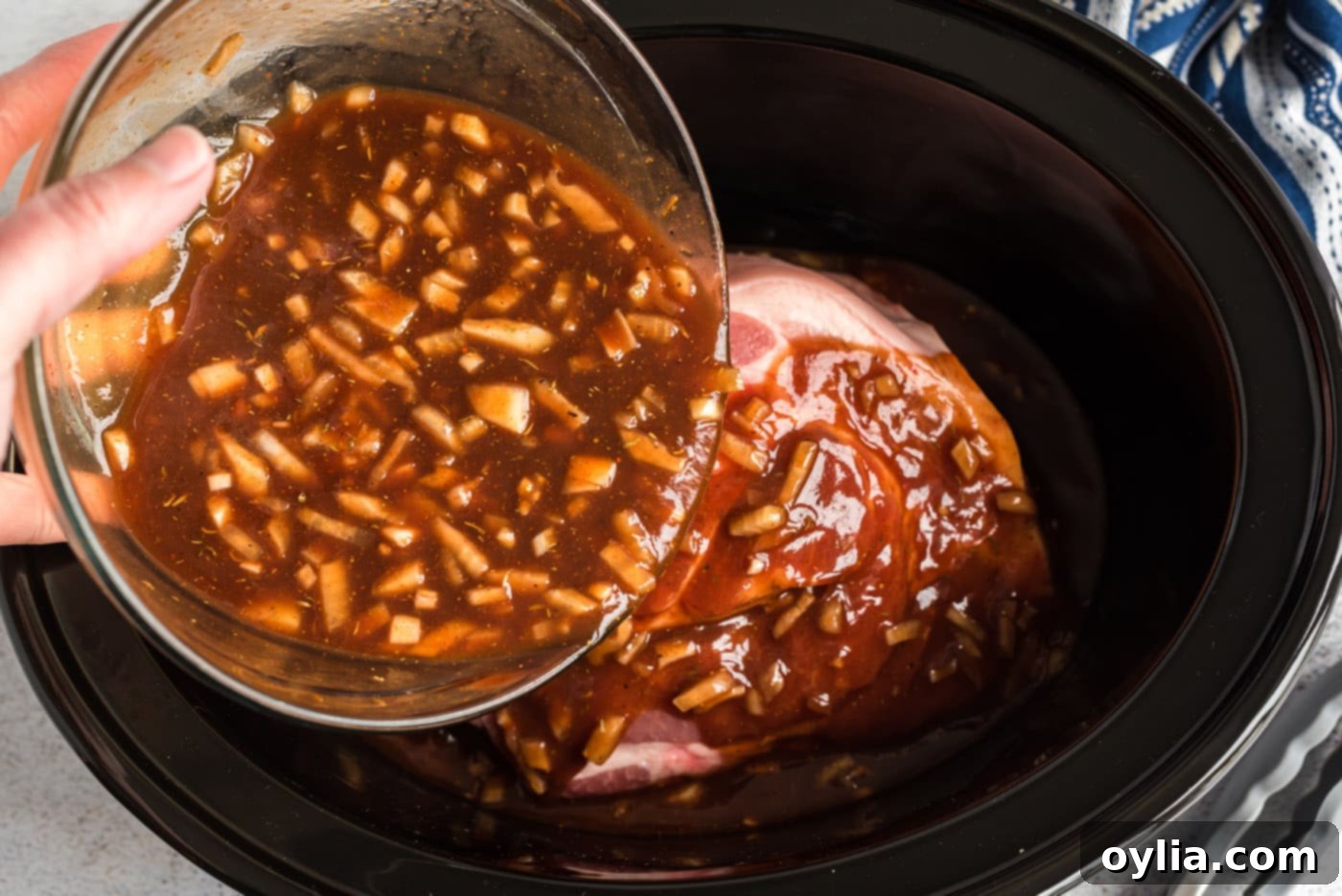 Easy Slow Cooker Pulled Pork 7 Pouring barbecue sauce mixture over pork roast in slow cooker