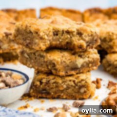 Close up photo of a stack of Brown Butter Chocolate Toffee Blondies with a bite taken out of the top one