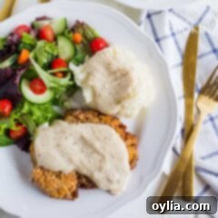 chicken fried steak with white gravy and salad on a plate