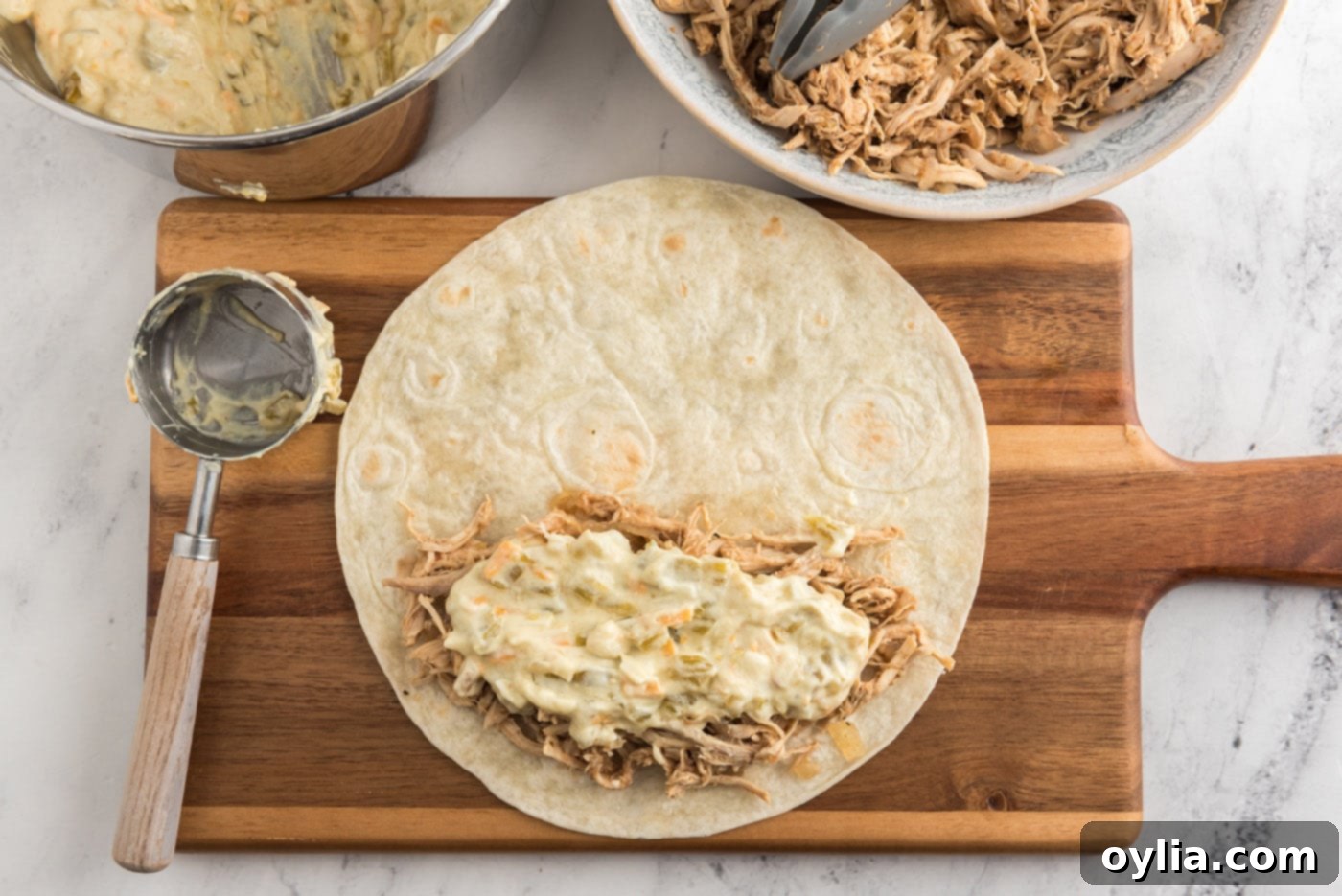 Creamy chile sauce spread on top of shredded chicken on a tortilla