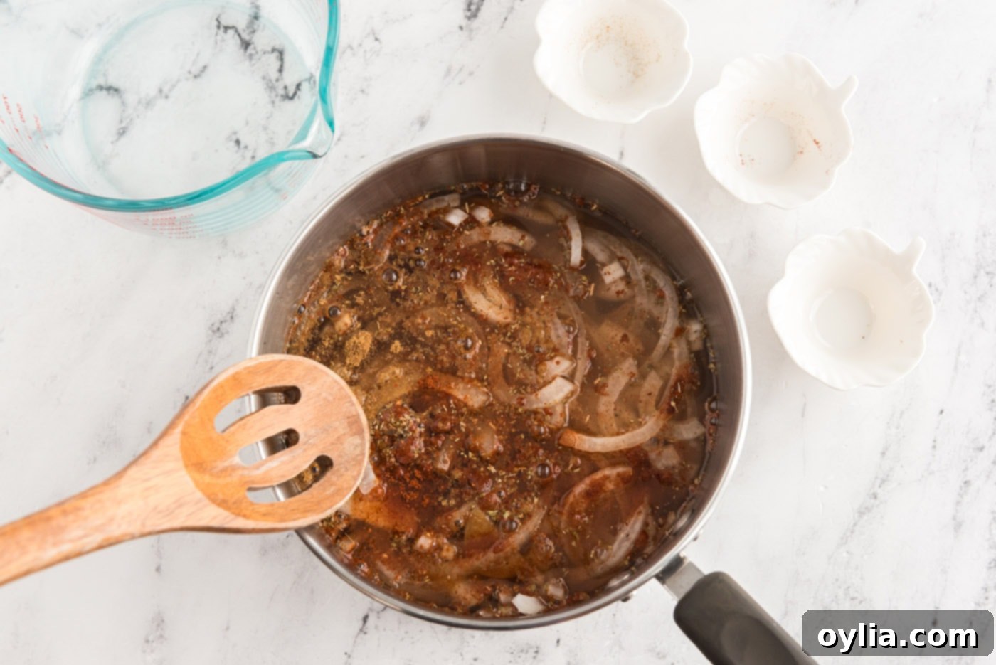 Reducing onion and chicken broth mixture in a saucepan