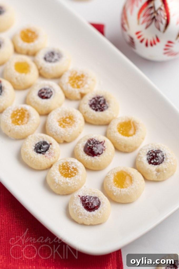 A tray filled with freshly baked thumbprint cookies, each with a vibrant jam center, ready to be cooled and served.