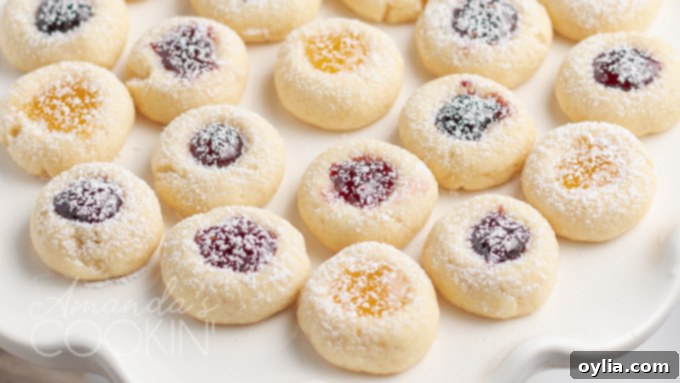 A beautiful close-up of finished thumbprint cookies, showing their perfect shape, golden color, and glistening jam centers.