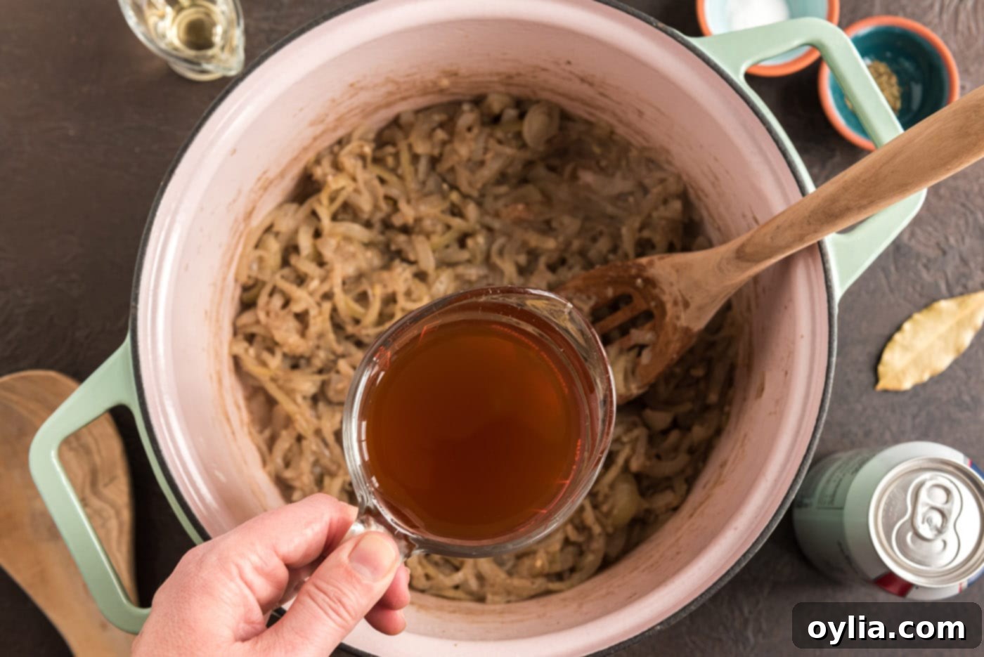 pouring broth into dutch oven with onion mixture