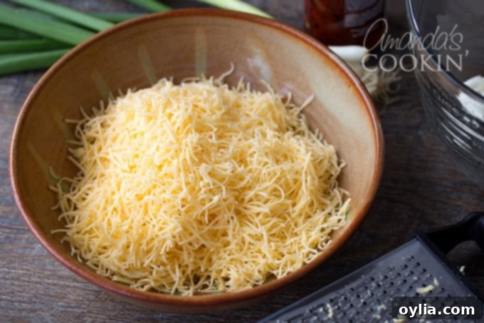 A large mixing bowl containing softened cream cheese and shredded Gouda cheese, ready to be combined into the base for the cheese ball.