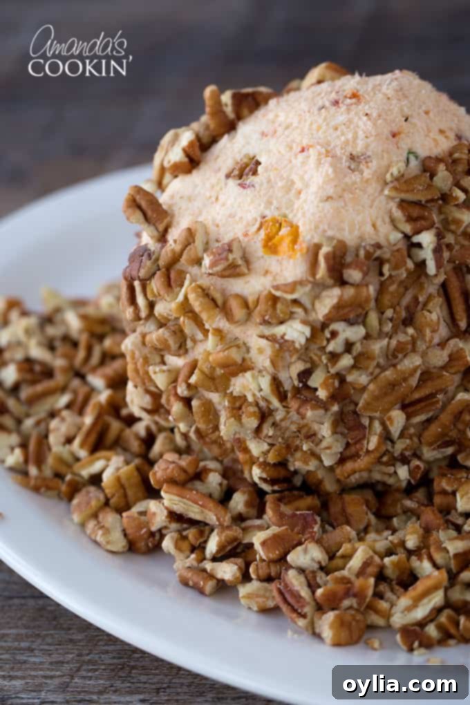 A cheese ball being rolled in a bowl of chopped pecans, ensuring a generous and even coating for a crunchy exterior.