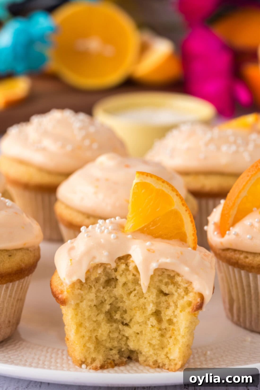 Sunshine Orange Creamsicle Cupcakes 2 Orange Creamsicle Cupcake with a bite taken out, revealing its fluffy interior and creamy frosting