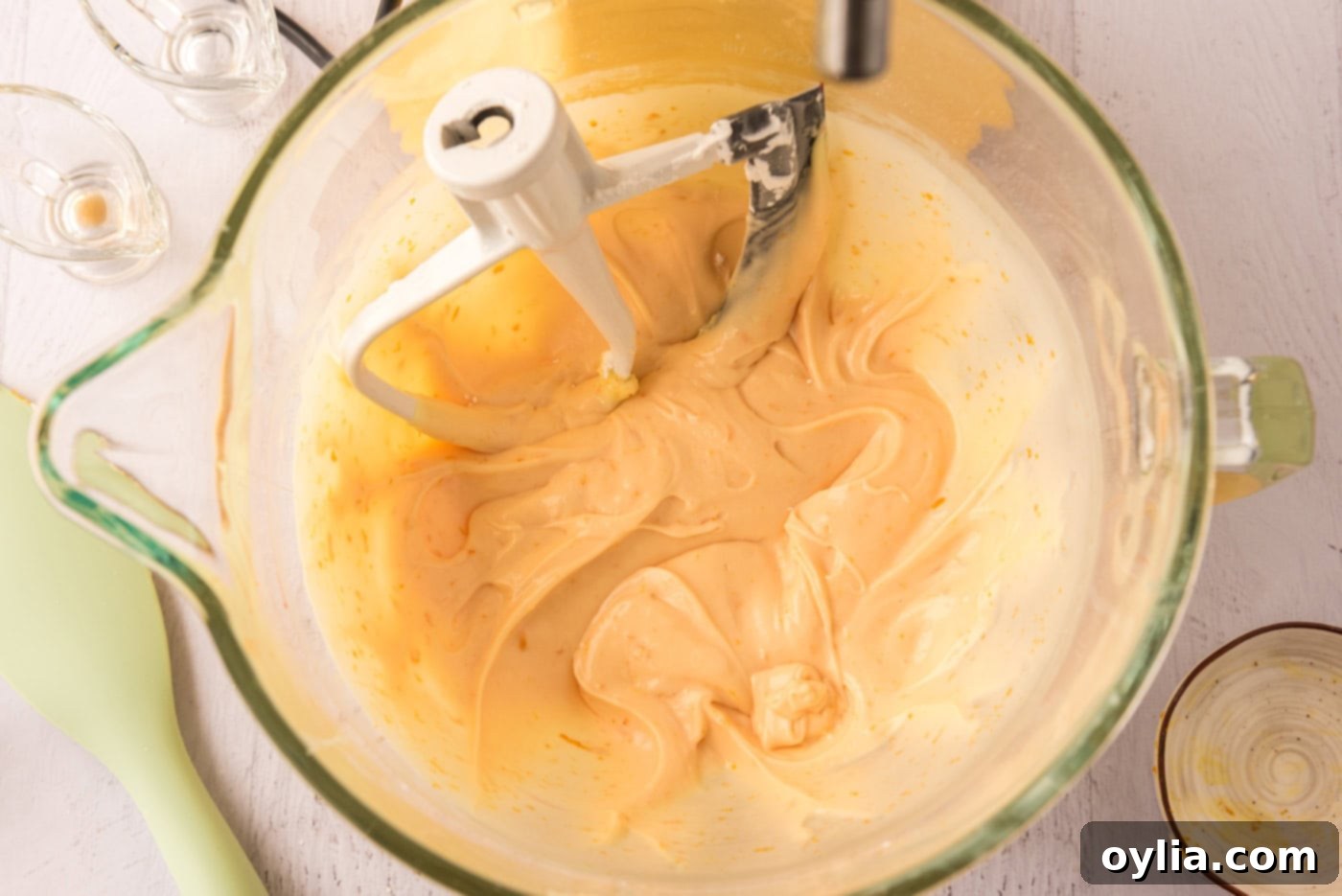 Orange creamsicle frosting in a stand mixer bowl, showing its creamy texture and vibrant color.