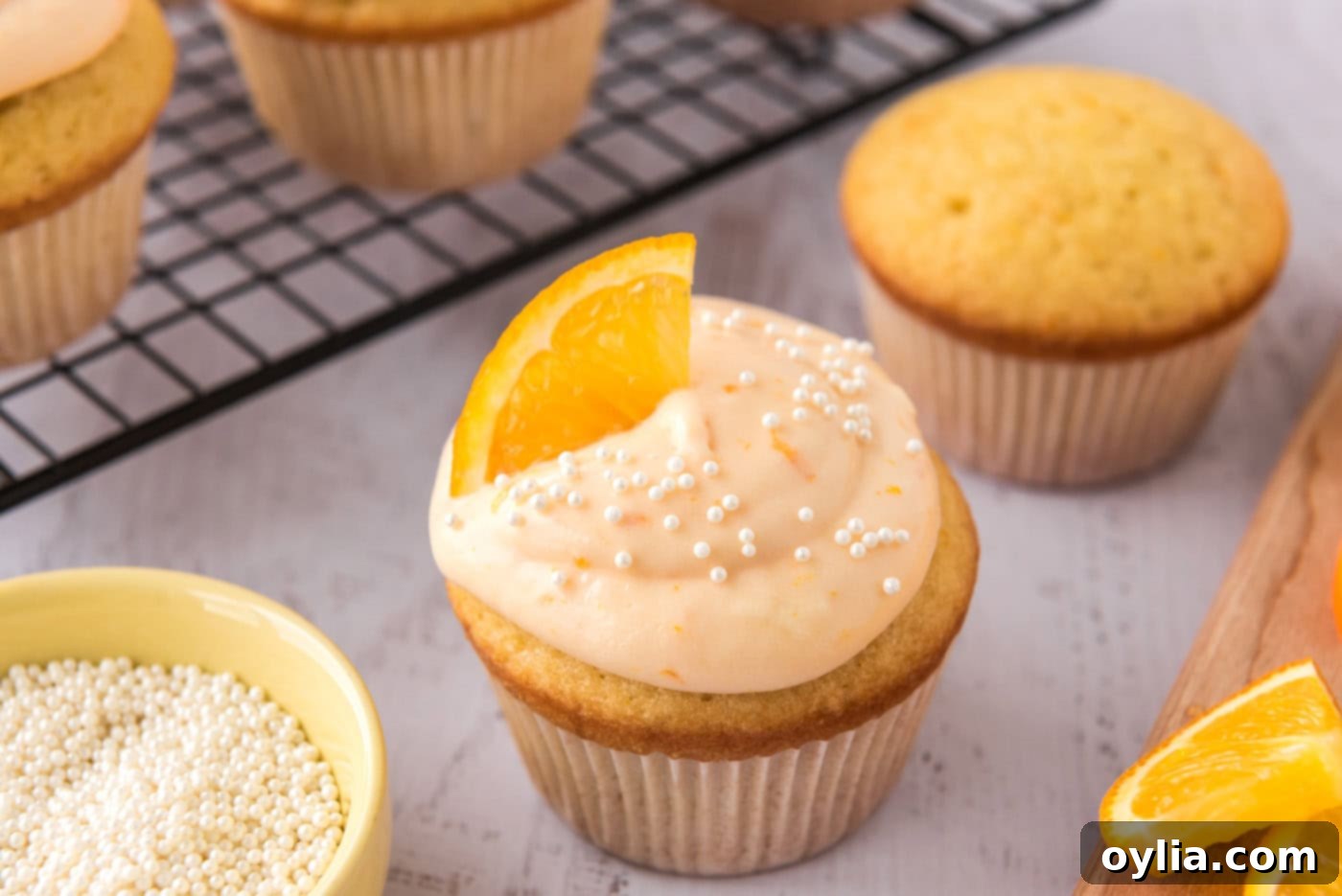 Finished creamsicle cupcakes garnished with a fresh orange wedge and colorful sprinkles, ready to be served.