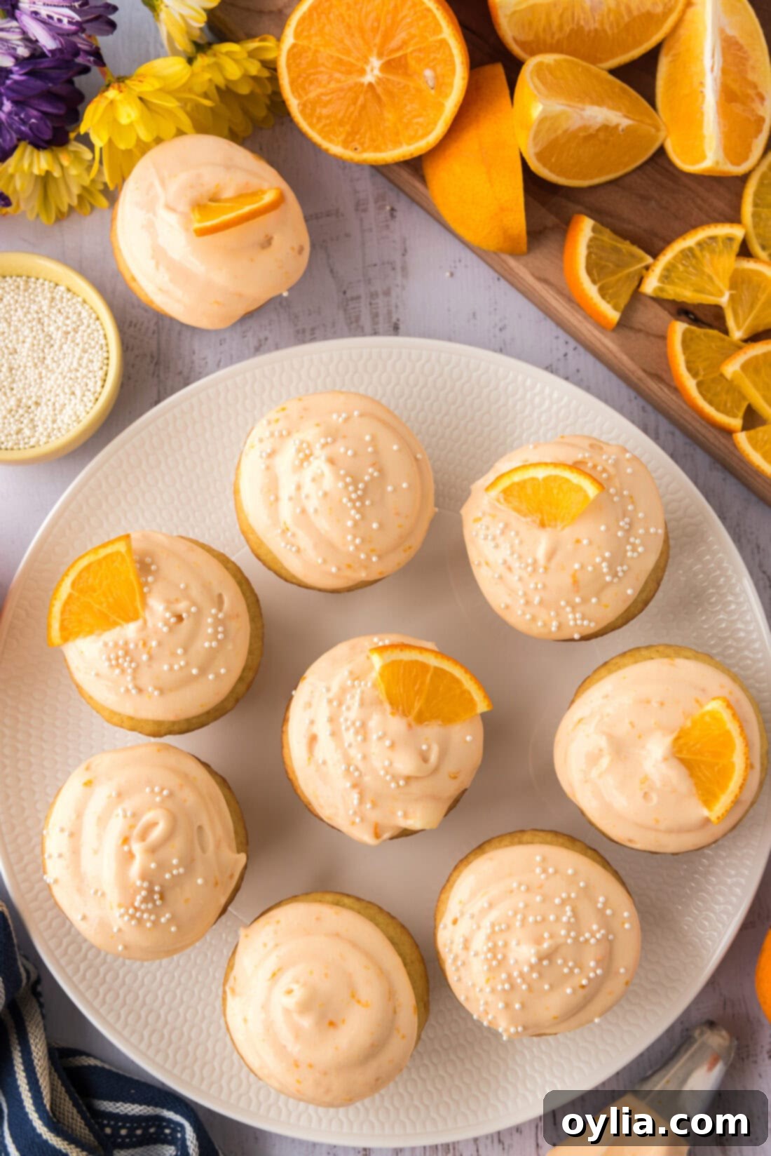 Sunshine Orange Creamsicle Cupcakes 15 A beautifully arranged plate of Orange Creamsicle Cupcakes, garnished with orange wedges and sprinkles, ready for serving.