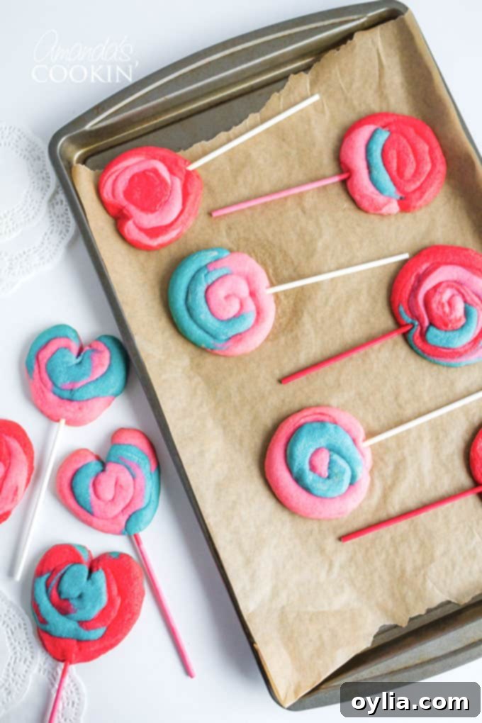 Colorful Valentine Play Dough Cookie Pops on a baking sheet, ready for the oven, showcasing their vibrant swirls