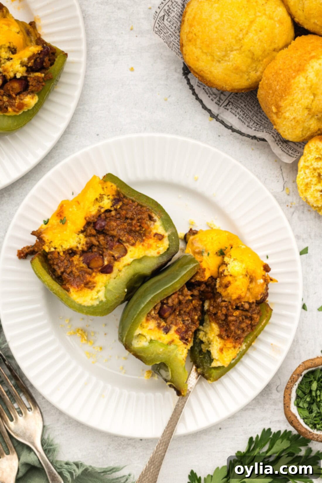 Chili and Cornbread Stuffed Pepper cut in half on a plate, showing the layers of chili, cornbread, and melted cheese