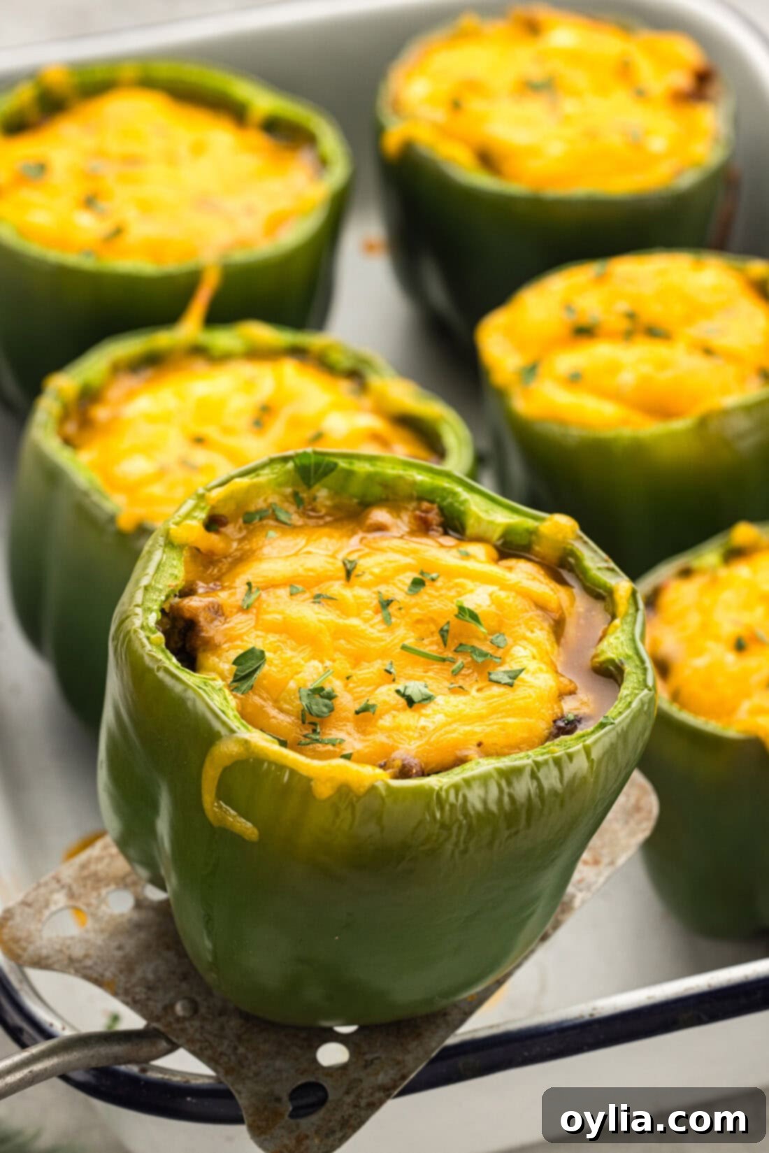 Chili and Cornbread Stuffed Pepper being lifted out of the pan with a spatula, showing the golden-brown top