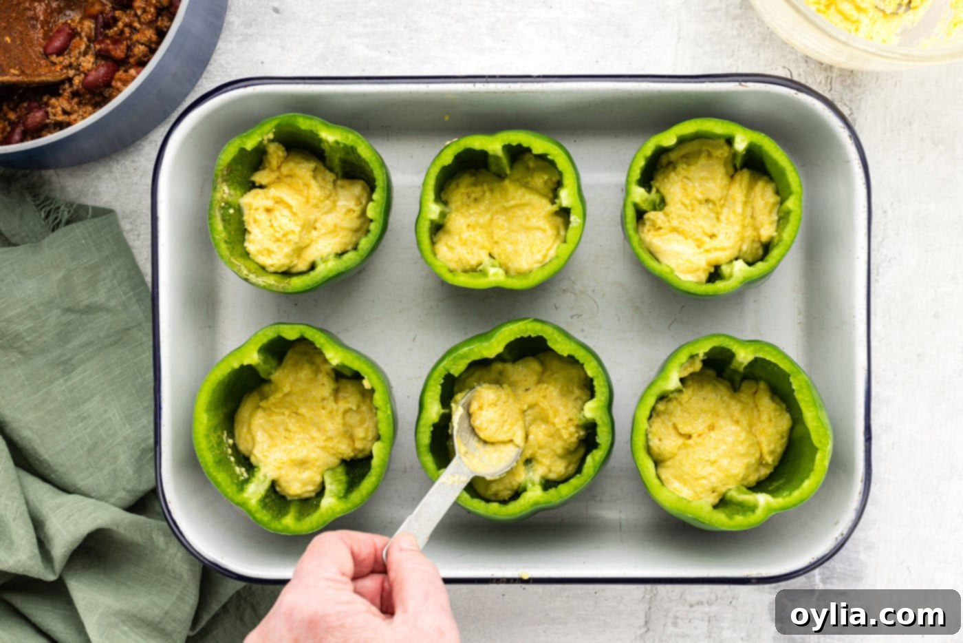 spooning cornbread batter into hollowed out bell peppers