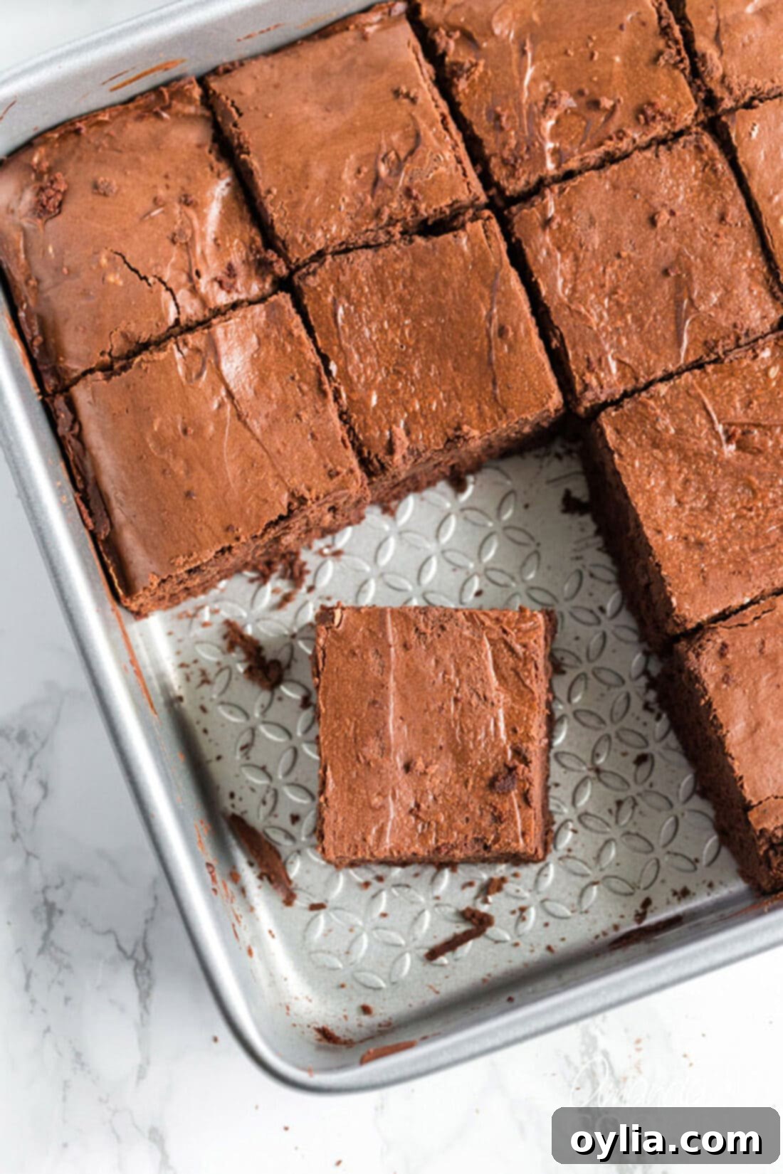 Pan of freshly baked Chocolate Cheesecake Brownies with a few squares neatly removed, revealing the delicious layers