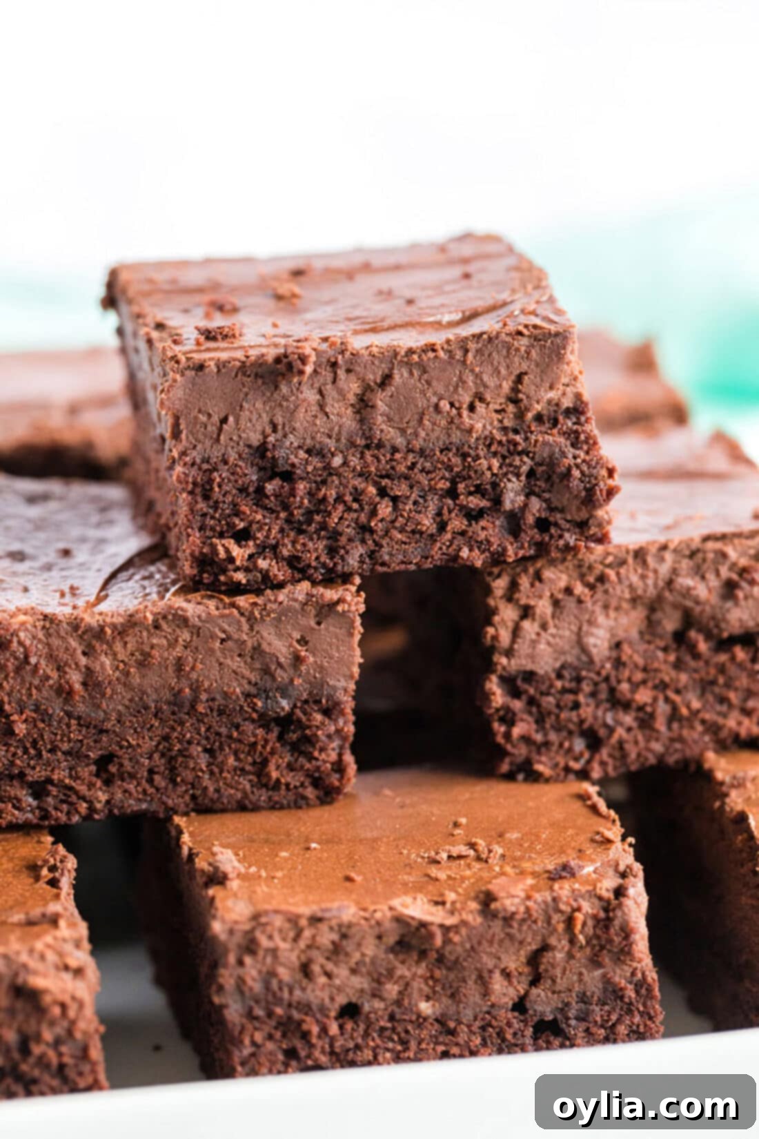 Stack of three decadent Chocolate Cheesecake Brownies on a white surface