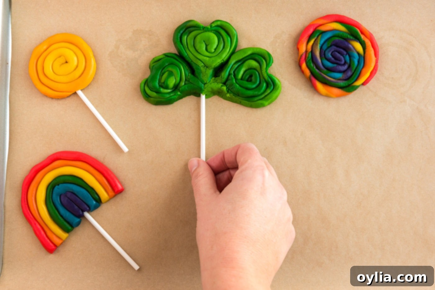 Adding lollipop sticks to shaped shamrock cookies before baking.