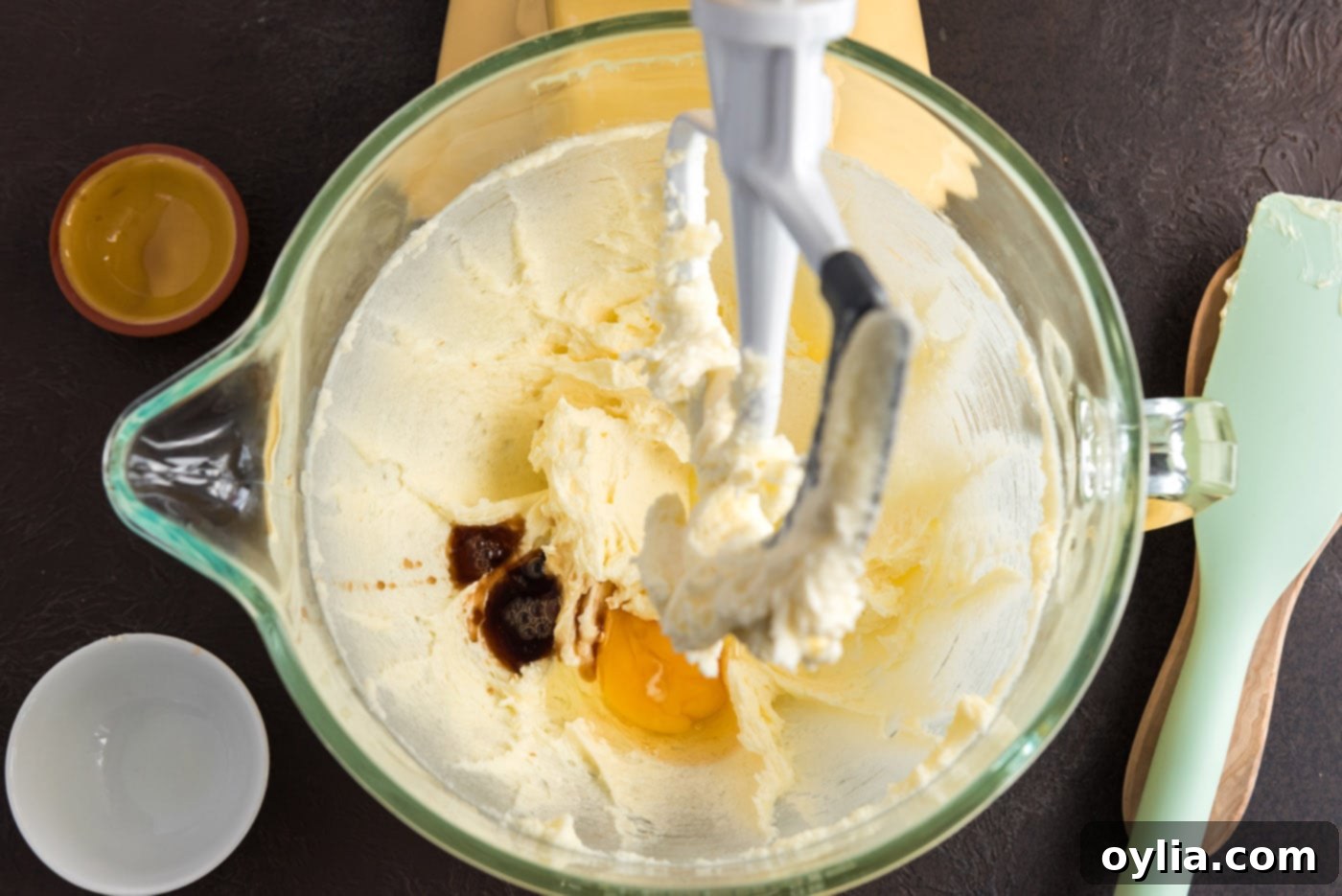 Creamed butter, cream cheese, sugar, and vanilla in a bowl with egg, ready to be beaten.