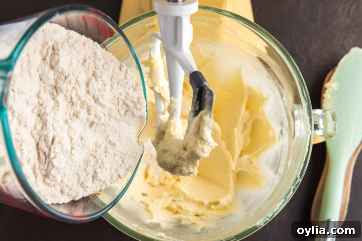 Adding dry ingredients to wet ingredients in a stand mixer to form the cookie dough.