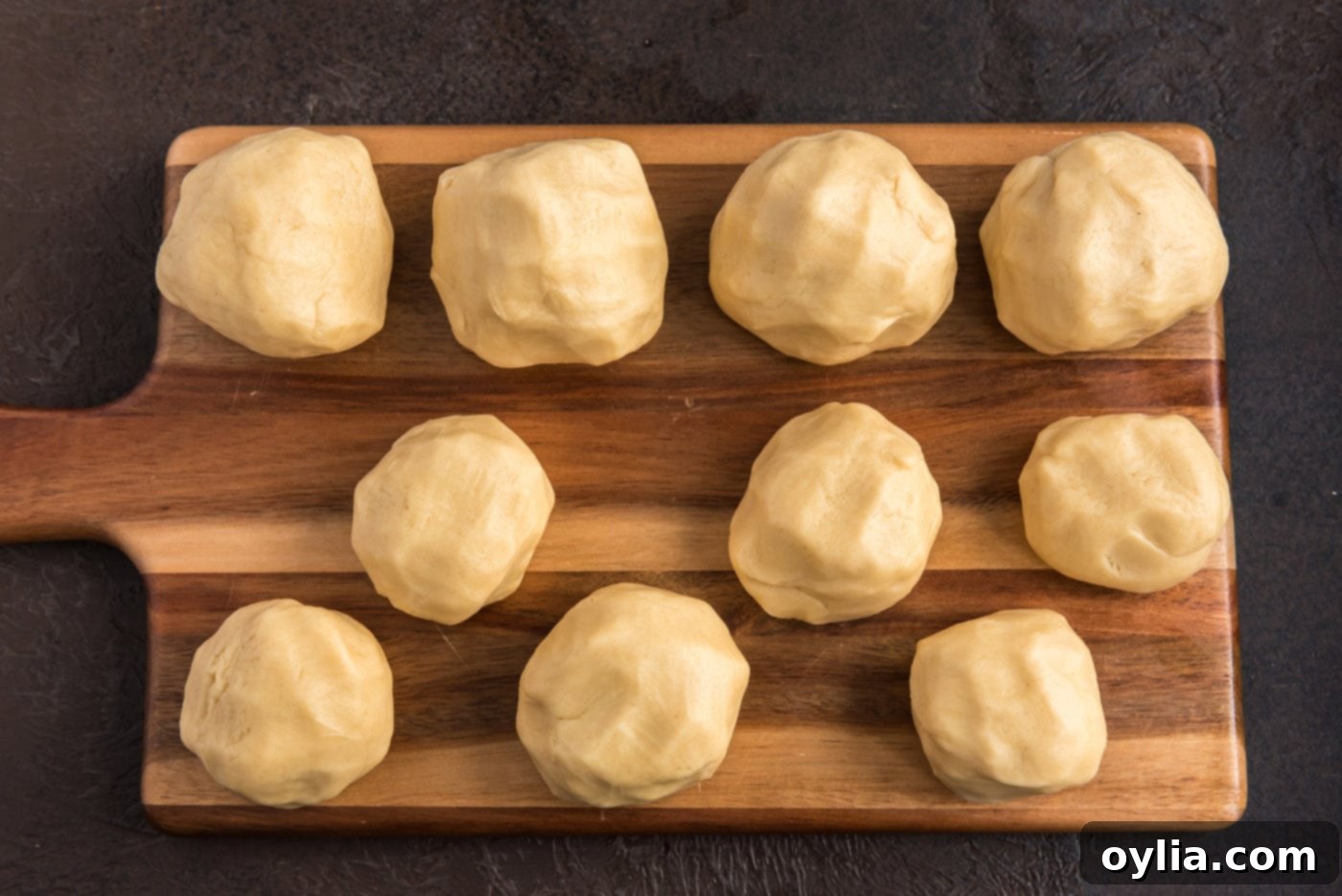 Sugar cookie dough balls, separated on a cutting board, ready for coloring.