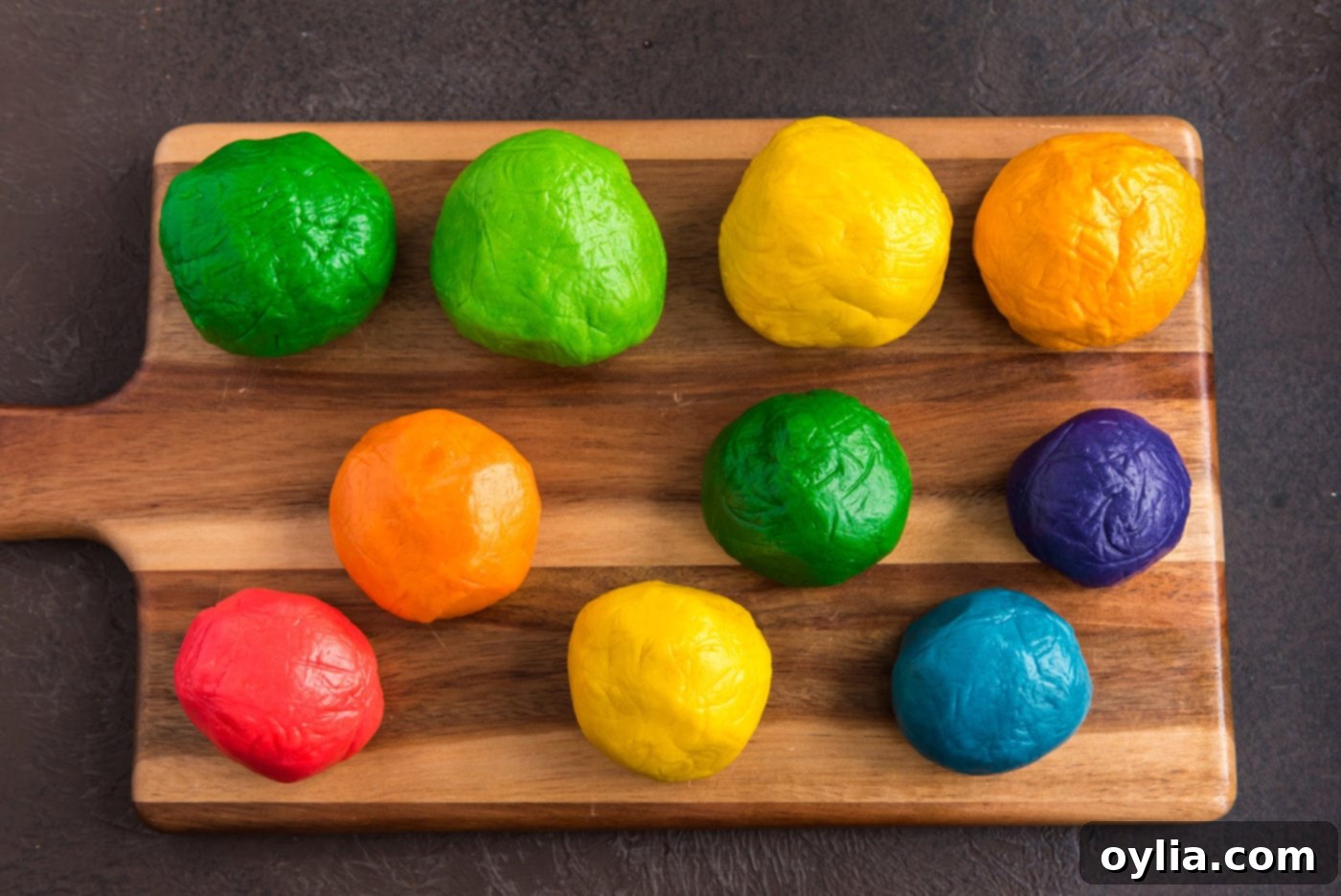 Colored sugar cookie dough balls in various shades of green, yellow, and rainbow colors.