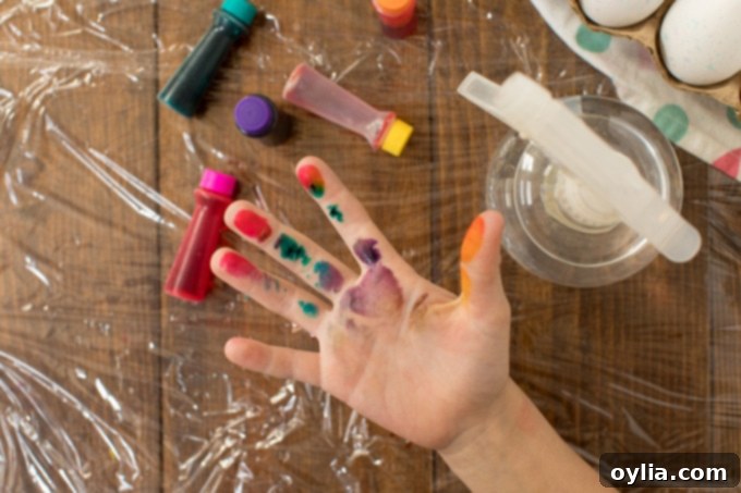 A hand stained with various colors of food coloring, showcasing the hands-on and potentially messy nature of tie-dye egg crafting