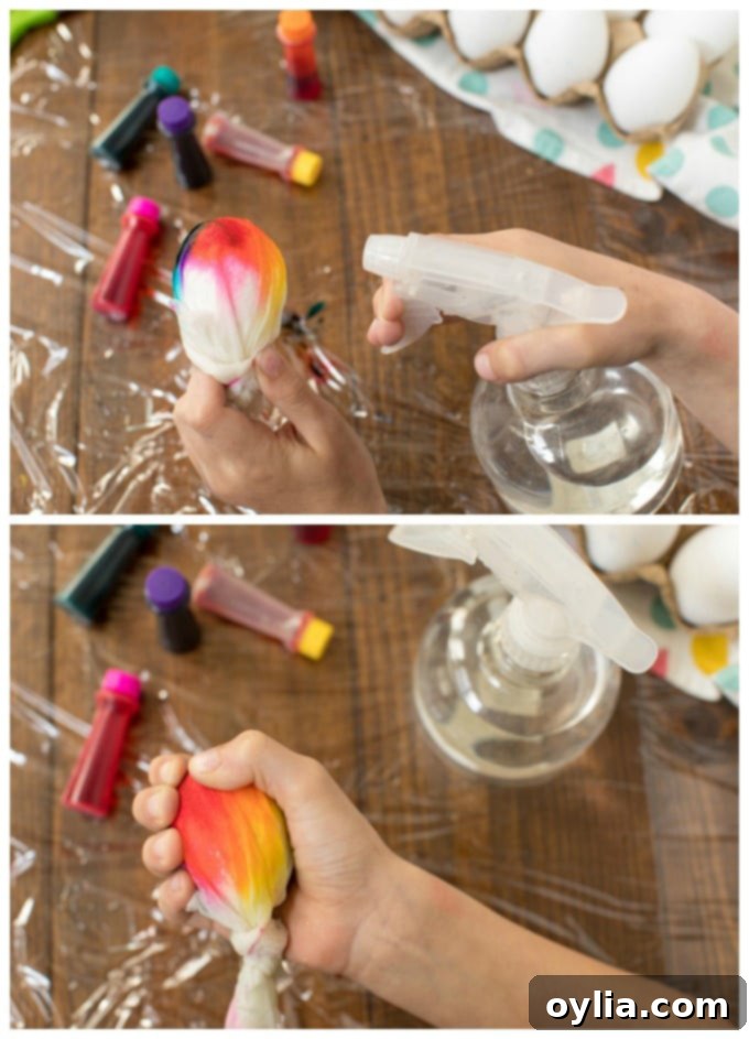 An egg wrapped in a multi-colored paper towel being sprayed with water to help the dye spread and create a tie-dye effect