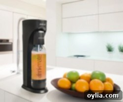 A bowl of fresh oranges on a kitchen counter, with a Drinkmate Beverage Carbonation Maker and a carbonated drink beside it.