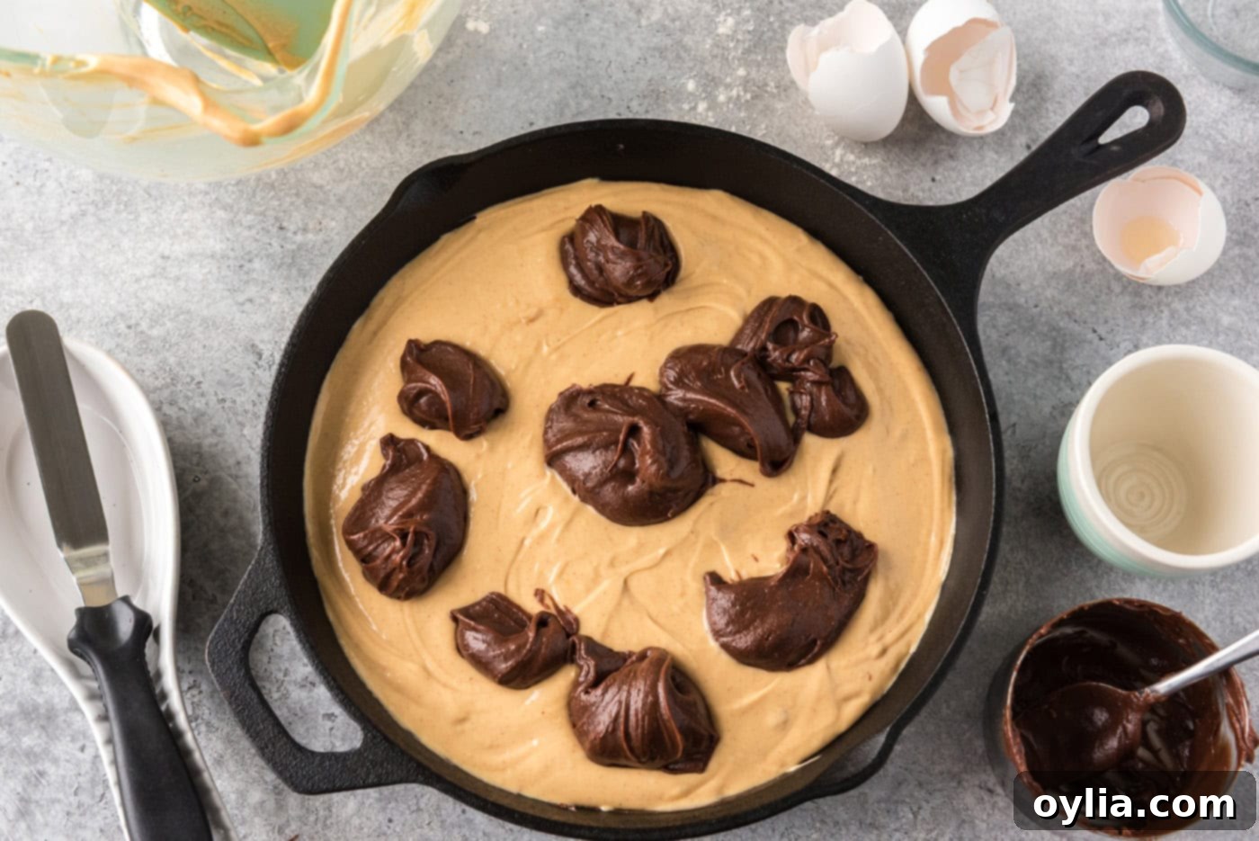dollops of brownie batter on top of peanut butter mixture in a cast iron skillet