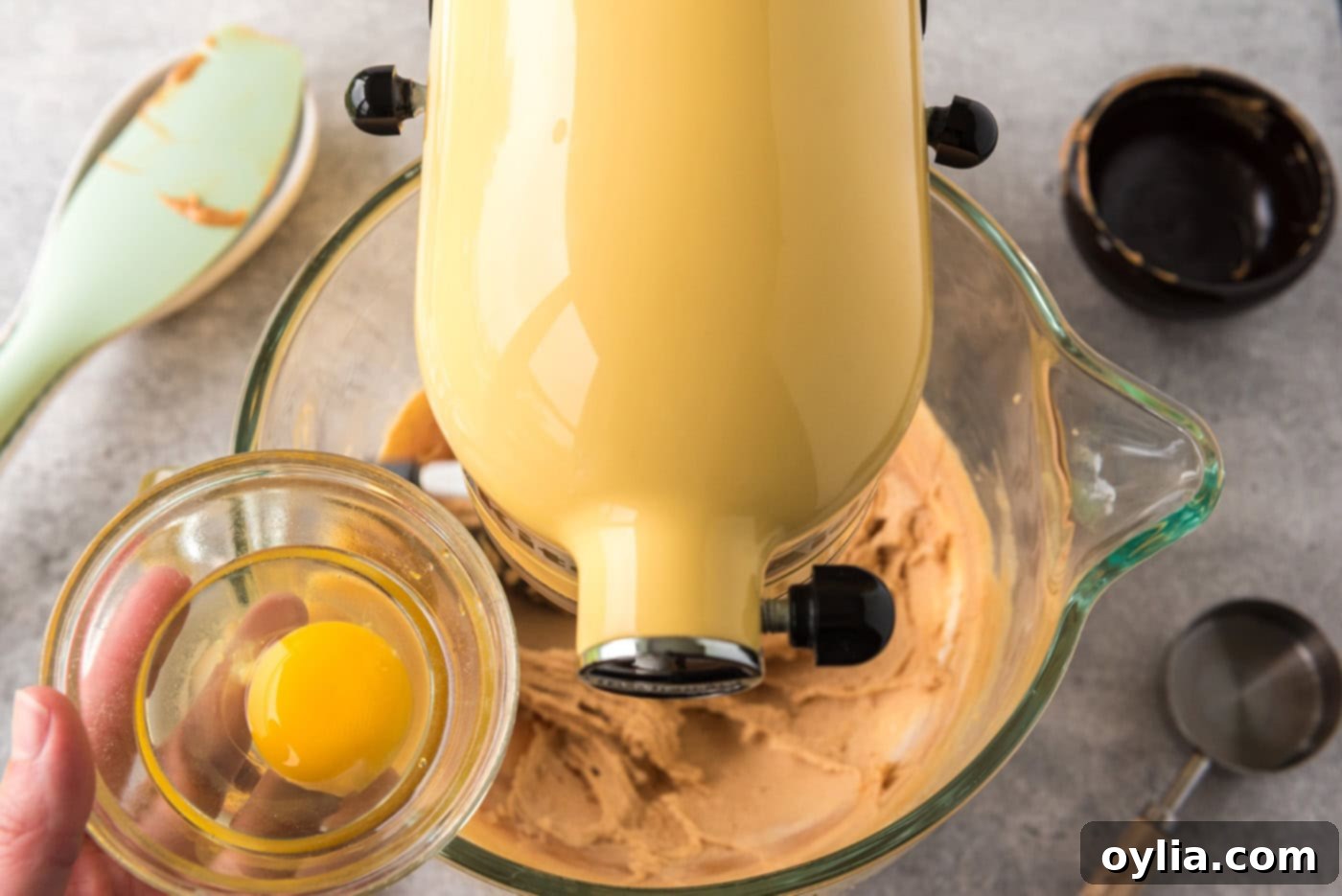 Adding eggs to a mixer bowl with peanut butter and cream cheese mixture
