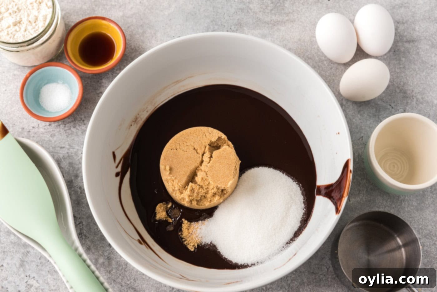 Brown sugar and granulated sugar added to melted chocolate mixture in a bowl