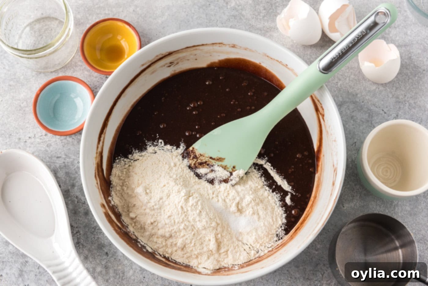 dry ingredients added to a bowl of brownie batter with a rubber spatula