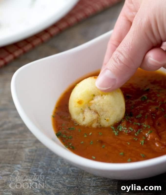 A pizza puff being dunked in a white bowl of pizza sauce.