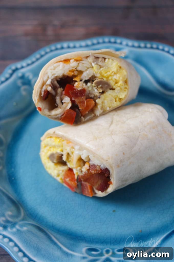A close up picture of a breakfast burrito cut in half resting on a blue plate.
