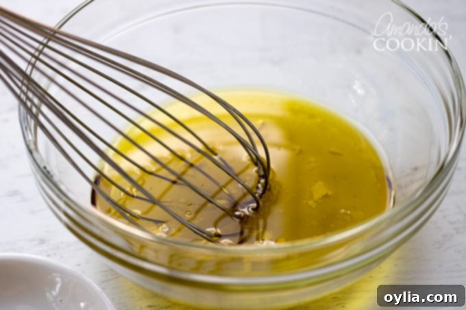 A small bowl with olive oil, vinegars, and mayonnaise, being whisked to create the salad dressing.