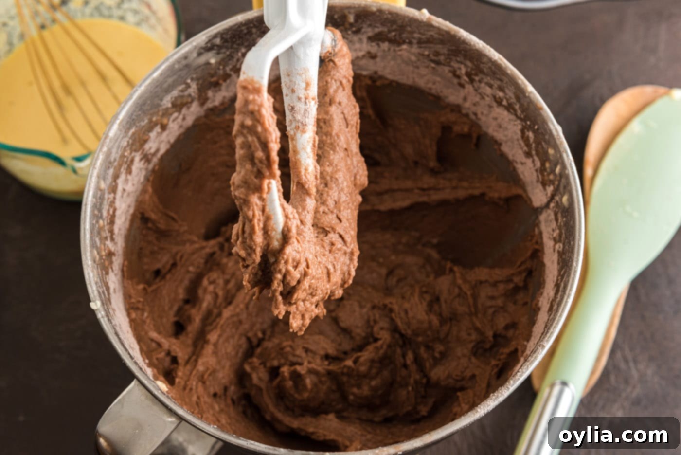 Dark, rich chocolate cake batter is smoothly mixed in a large bowl, showcasing its consistent texture before adding the final wet ingredients.