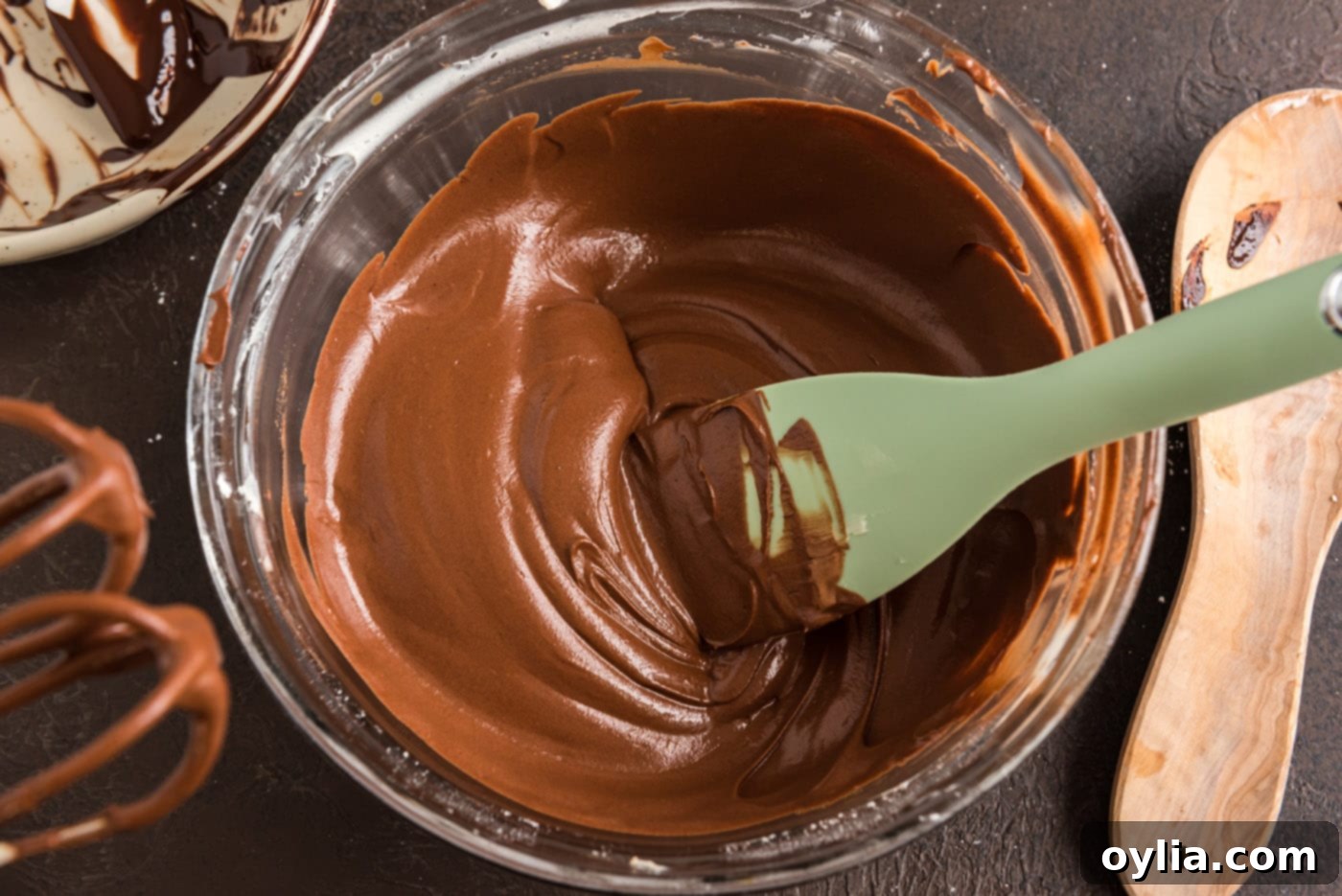 A bowl of perfectly smooth, glossy, and rich chocolate fudge frosting, showcasing its invitingly silky texture ready for icing the cake.
